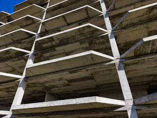 Concrete structure shows support beams under a blue sky in an urban setting during daylight hours