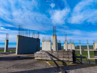 Construction site with concrete pillars and steel reinforcement under a blue sky in an open area during daytime