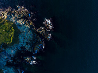 Coastal view showing rocky shoreline and dark ocean water with some waves during daylight