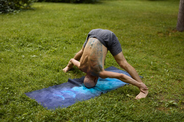 Person in deep forward bend relaxing on grassy park surface