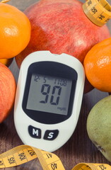 Glucose meter with sugar level, fresh fruits and tape measure. Healthy lifestyle and nutrition during diabetes