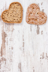 Fresh wholegrain bread in shape of heart for breakfast. Place for text on rustic background