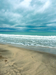 Cloudy sky over beach with ocean waves and sandy shore during early morning hours near coastal area