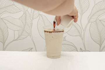 The silky texture and subtle beige and light brown tones of an artistic latte, where the foam traces a fern leaf against the dark background of the coffee.