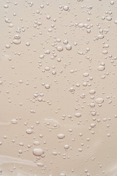 Clear gel texture with air bubbles on beige background