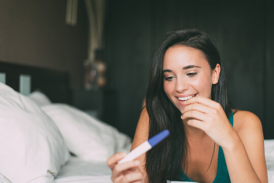 Woman relaxing at home holding a pregnancy test