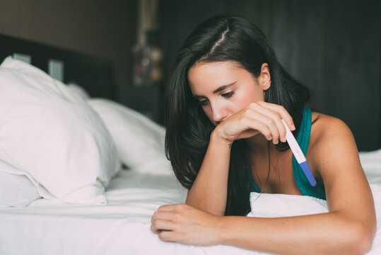 Woman reflecting at home holding a pregnancy test