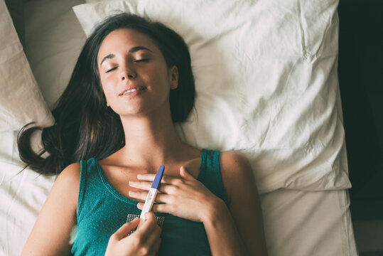 Woman relaxing at home with a positive pregnancy test