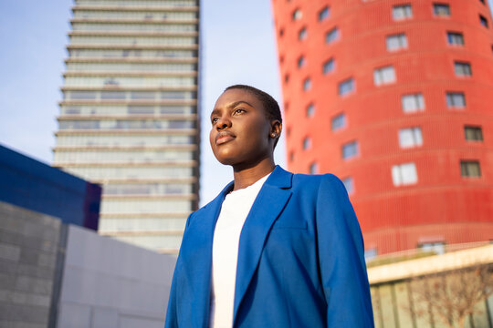 Confident CEO standing with modern office buildings