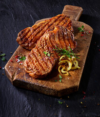  Rindfleisch im Talgmantel mit Grillstreifen auf rustikaler Holzplatte und auf Schiefer