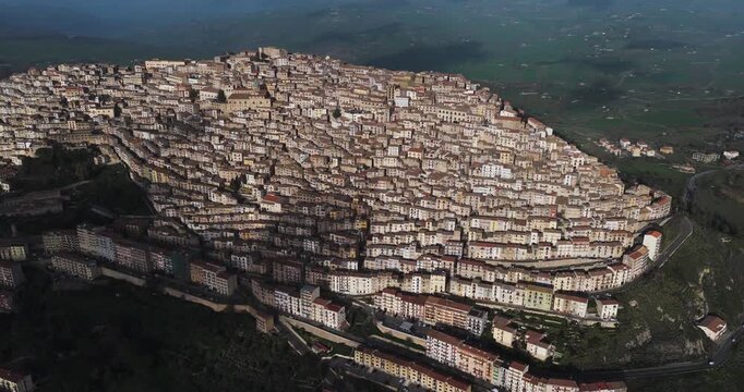 Aerial view of the dense cluster of buildings cascading down the hillside, a symphony of terracotta rooftops and sun-kissed walls, Gangi, Sicily, Italy.