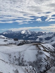 Snowy mountains under a partly cloudy sky with rugged terrain, perfect for winter sports background