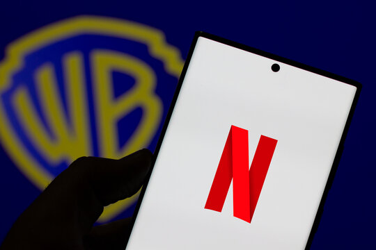 Netflix's N logo on Smartphone Screen with Warner Logo Behind