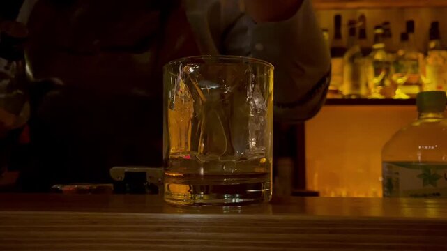 バーで氷の入ったグラスにお酒を注ぐ様子