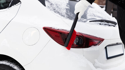 Snow brush on rear car light in winter © Ilona