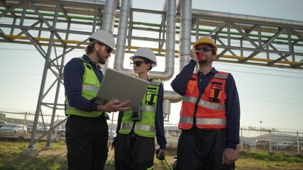 Workers discuss project details in industrial setting during afternoon hours
