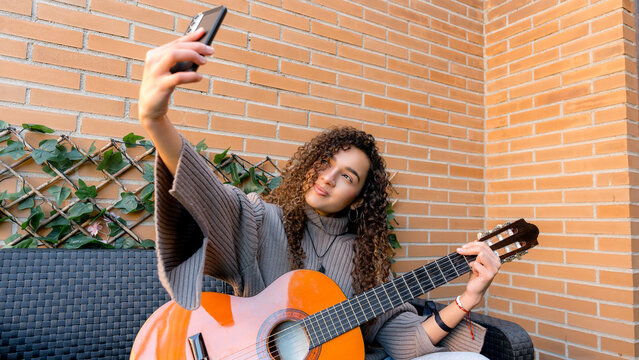 Young woman joyfully playing guitar and capturing moments