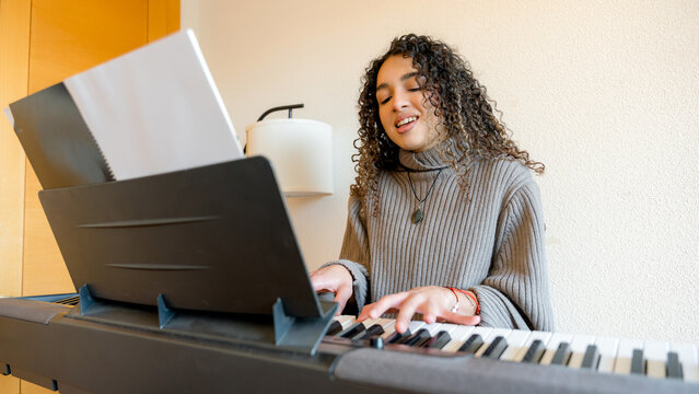 Young woman playing piano in cozy home setting