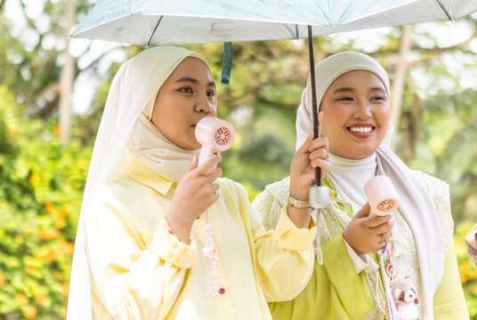 Women filming muslim music video outdoors with hand fans