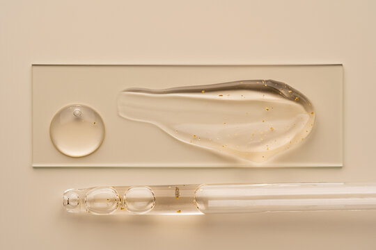 Cosmetic gel texture with golden specks and glass pipette
