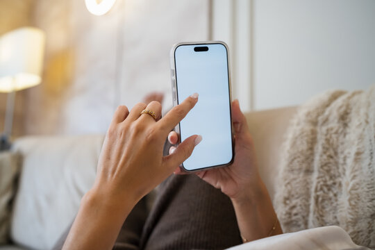 Woman using smartphone on a cozy sofa