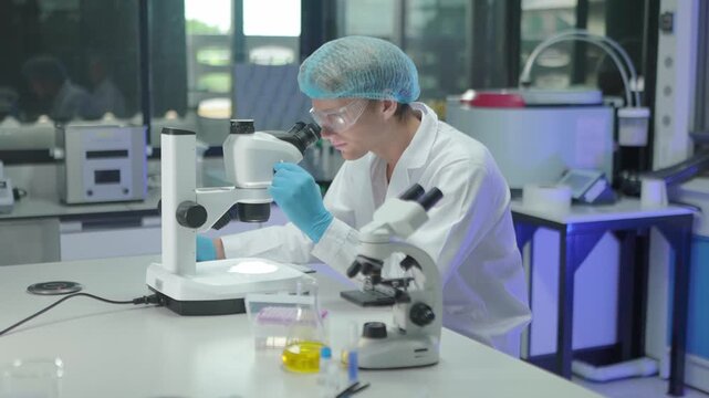 Scientists work in lab using microscope and examining samples while discussing findings together