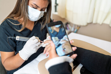 Manicurist performing nail care service at beauty salon