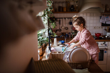 Independent child doing dishes at home.