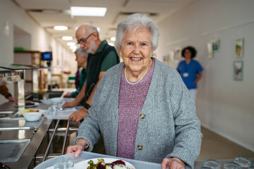 Group of seniors having lunch in community center cafeteria.