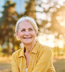 Portrait of an elderly woman outdoors. Happy senior woman sitting on a bench in park