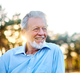 Portrait of an elderly man outdoors. Happy senior man sitting on a bench  in park