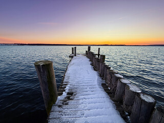 winter beach at sunset with unique frozen wooden pier