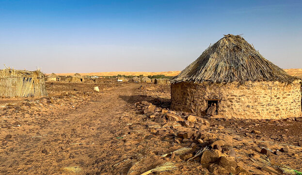 Village in the Mauritanian desert. A round hut made of stones with a thatched roof.
