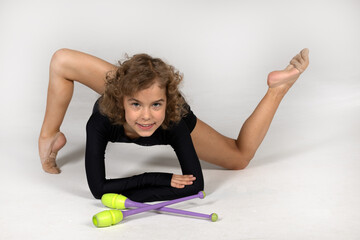 A girl gymnast demonstrates exercises with clubs.