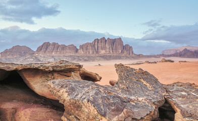 Orange sandstone rocks formations in Wadi Rum (also known as Valley of the Moon) desert, Jordan, camp tents under mountains at distance
