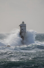 Powerful ocean waves crashing against a lighthouse during intense sea storm