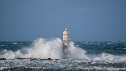 Powerful ocean waves crashing against a lighthouse during intense sea storm