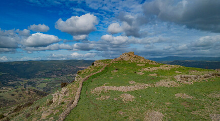 Prehistoric nuraghe stone structure rising from green landscape under dramatic sky in Sardinia