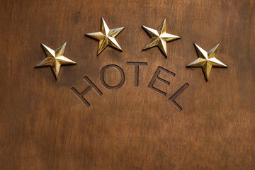 4 Four golden stars of hotel ranking in a row isolated on brown wooden wall background, five star rating and quality concept