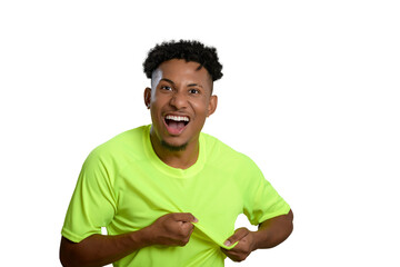 Energetic young man in a bright neon green t-shirt smiling, holding the t-shirt to show the location of the team crest.