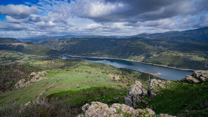 Prehistoric nuraghe stone structure rising from green landscape under dramatic sky in Sardinia