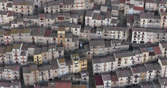 Aerial view of tightly packed buildings with varied roof textures and colors creating an intricate pattern, Gangi, Sicily, Italy.