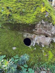 Prehistoric nuraghe stone structure rising from green landscape under dramatic sky in Sardinia