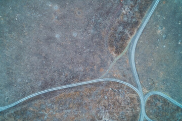 Aerial country dirt road junction winding through dry autumn fields with rough soil texture featuring lonely rural landscape top down view