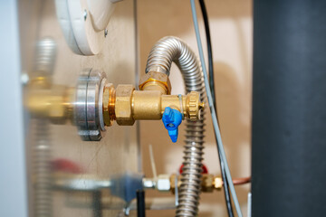 Brass valve with blue handle connected to plumbing system in indoor setting during daylight