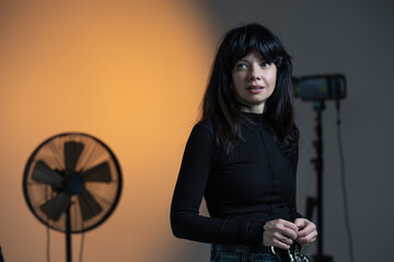A young brunette poses for a photographer and looks into the camera. A woman poses in a photo studio.