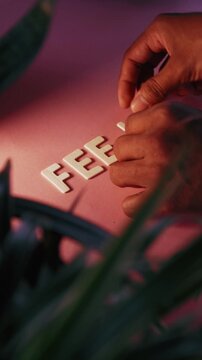 Person's hands spelling the word feel on a pink table