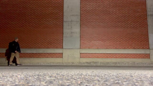 Solo man walking against a brick wall at night 
