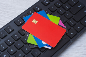 Stack of colorful credit and debit cards lying on black computer keyboard, illustrating concept of online payment, internet banking and e commerce purchases.