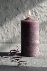 Minimalist purple candle with glowing flame on textured surface, evoking calm atmosphere and modern interior decor inspiration